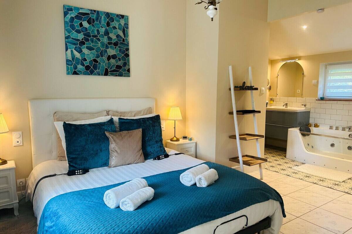 Une chambre d’hôtel avec un grand lit, une salle de bain avec une baignoire et un tableau au mur.