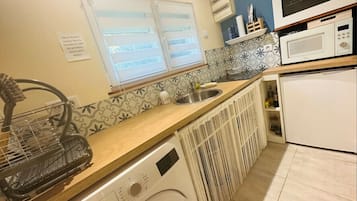 Uma cozinha compacta com máquina de lavar, pia e micro-ondas.