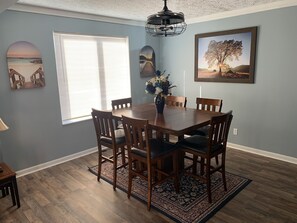 A dining area with a wooden table and chairs, a chandelier, and artwork on the walls. - Cincinnati/KY Airport-5Bed Vacation Home-close to Cincinnati, Ark, I71/75 (Florence)