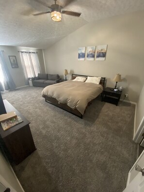 A bedroom with a bed, a nightstand, a desk, a ceiling fan, and a window with curtains. - Cincinnati/KY Airport-5Bed Vacation Home-close to Cincinnati, Ark, I71/75 (Florence)