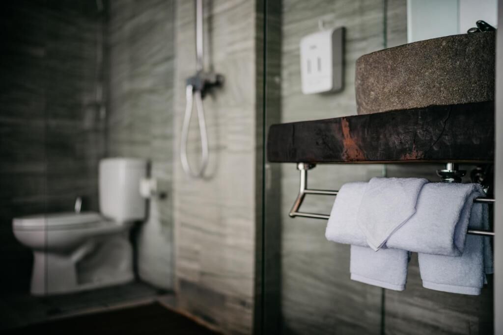 Un baño moderno con pared de mármol, inodoro y toallero con toallas dobladas.