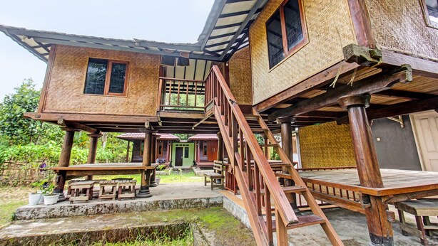Una casa de madera tradicional con balcón, escaleras y un pequeño porche.