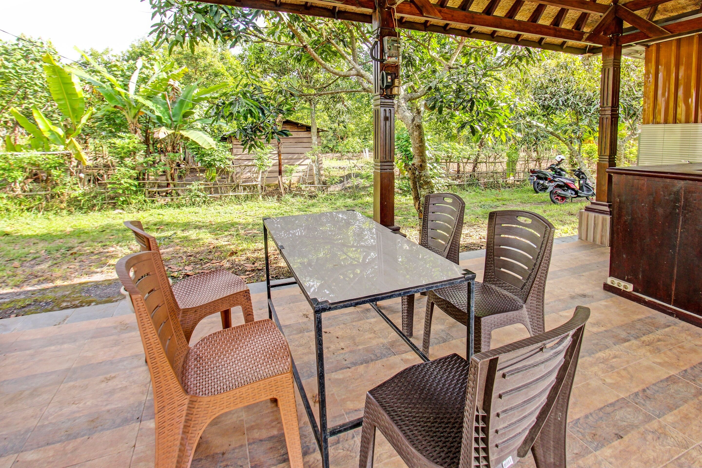 An outdoor patio with a table and chairs, surrounded by greenery and a wooden fence.