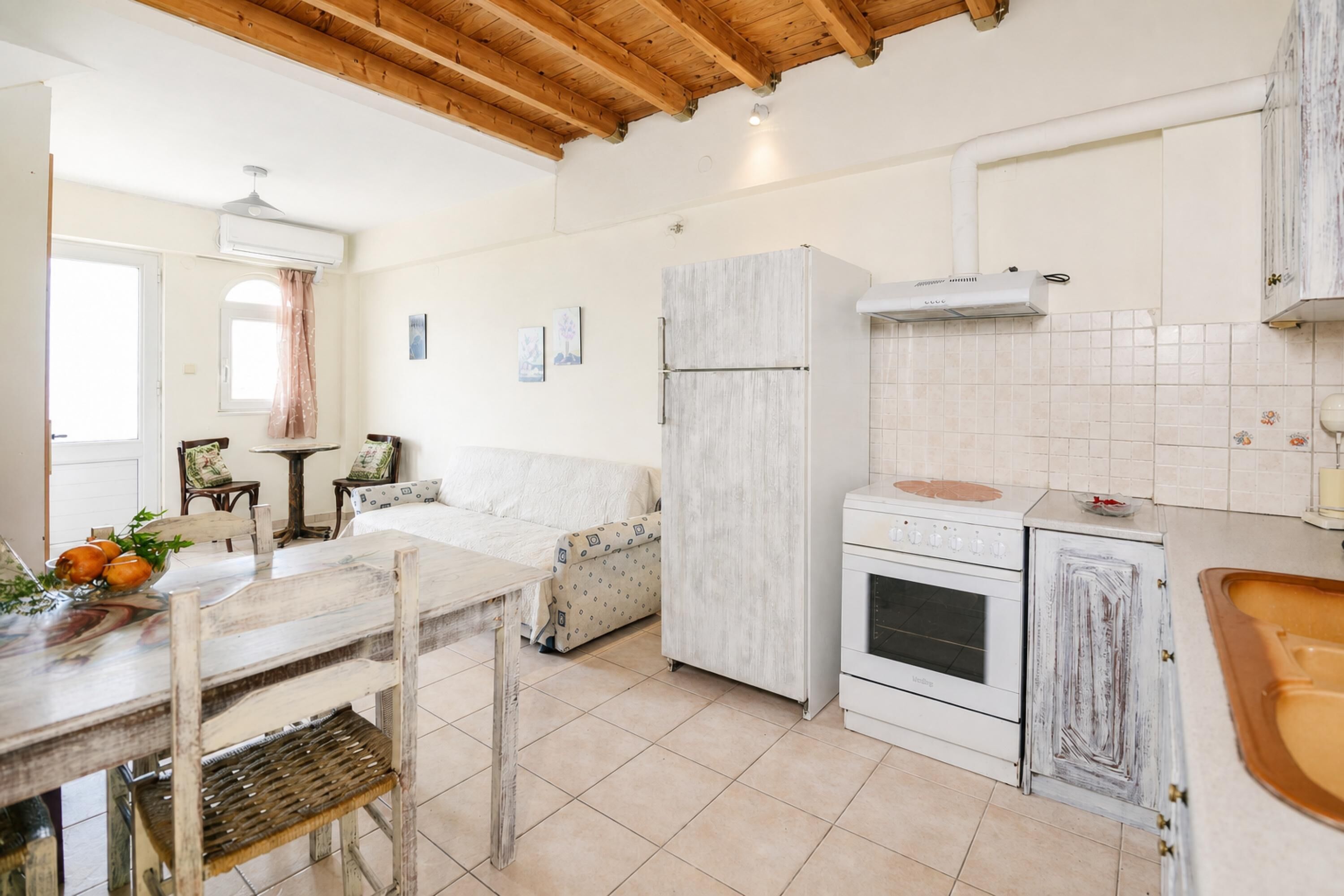 Une cuisine avec un plafond en bois, des armoires blanches, un réfrigérateur blanc et une cuisinière.
