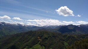 A mountainous landscape with snow-capped peaks and dense forested valleys. - Apartamentos Valdecarzana . Braña el Revellón Senda del oso (TEVERGA-OVIEDO-ASTURIAS)