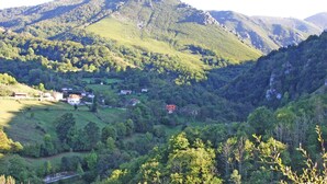 A mountainous landscape with scattered houses and greenery. - Apartamentos Valdecarzana . Braña el Revellón Senda del oso (TEVERGA-OVIEDO-ASTURIAS)