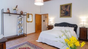 Un dormitorio con una cama, una puerta de madera, un espejo y un cuadro en la pared.