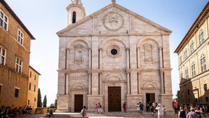 Una iglesia histórica con una imponente torre campanario y amplias ventanas de arco.