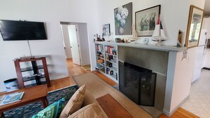 Una sala de estar con chimenea, televisor y estantería.