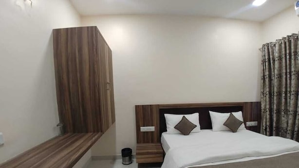 A bedroom with a bed, a wooden wardrobe, and a bedside table. - Hotel Matruchhaya Lonavala (Mawal)