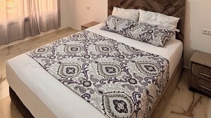 A bedroom with a bed, a nightstand, a wall-mounted artwork, and a ceiling light fixture. - Villa Avec Piscine Privée à Saidia (Saïdia)