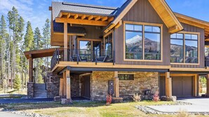 Une maison moderne à deux étages, avec des fondations en pierre, de grandes fenêtres et un balcon en bois.