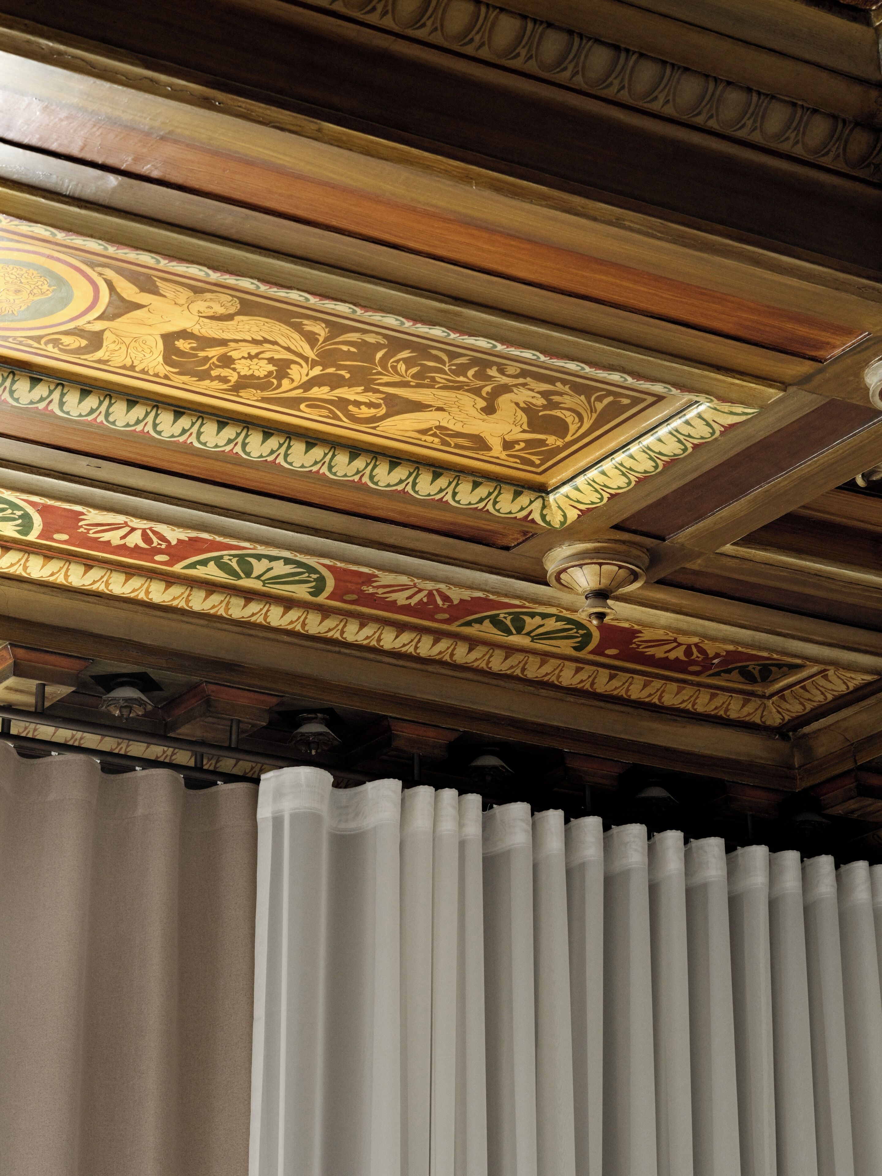 A ceiling with intricate wood paneling and decorative moldings.