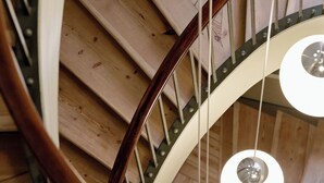 A spiral staircase with wooden steps and metal railings, leading to a lower level.