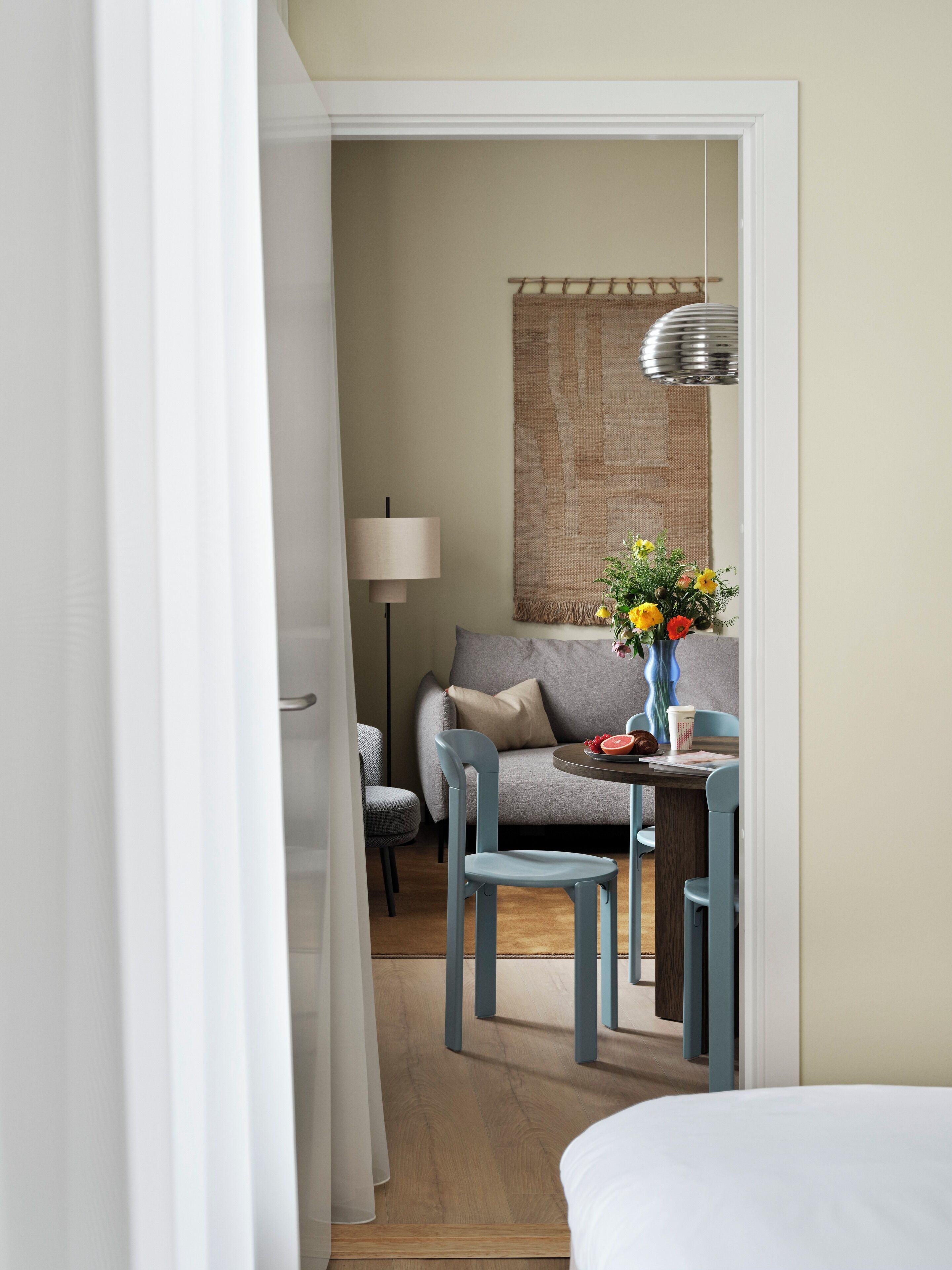 Ein Hotelzimmer mit einem Bett, einem Esstisch mit Stühlen, einem Sofa, einer Lampe und einem Wandbild.