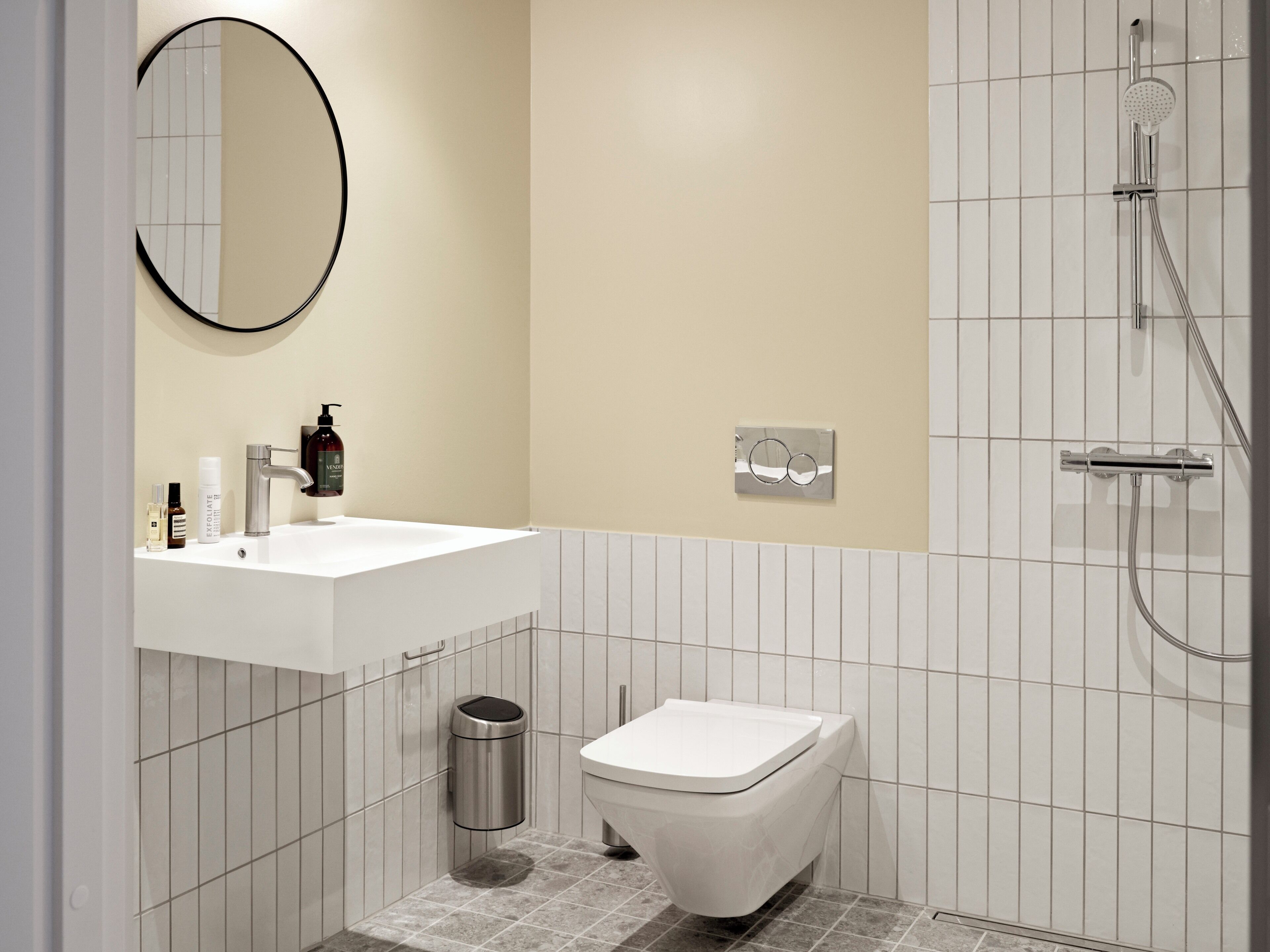 A modern bathroom with a white sink, a toilet, a mirror, and a shower.