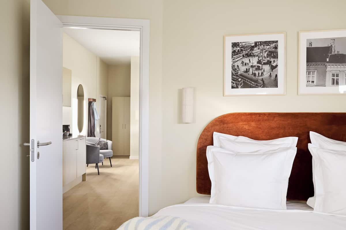 Een hotelkamer met een bed, een bureau en twee foto's in lijsten aan de muur.