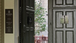 A hotel entrance with a sign indicating 'VENDERS COPENHAGEN' and a courtyard with outdoor seating.