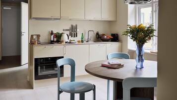 A modern kitchen with white cabinets, a dining table with blue chairs, and a vase with flowers on the table.