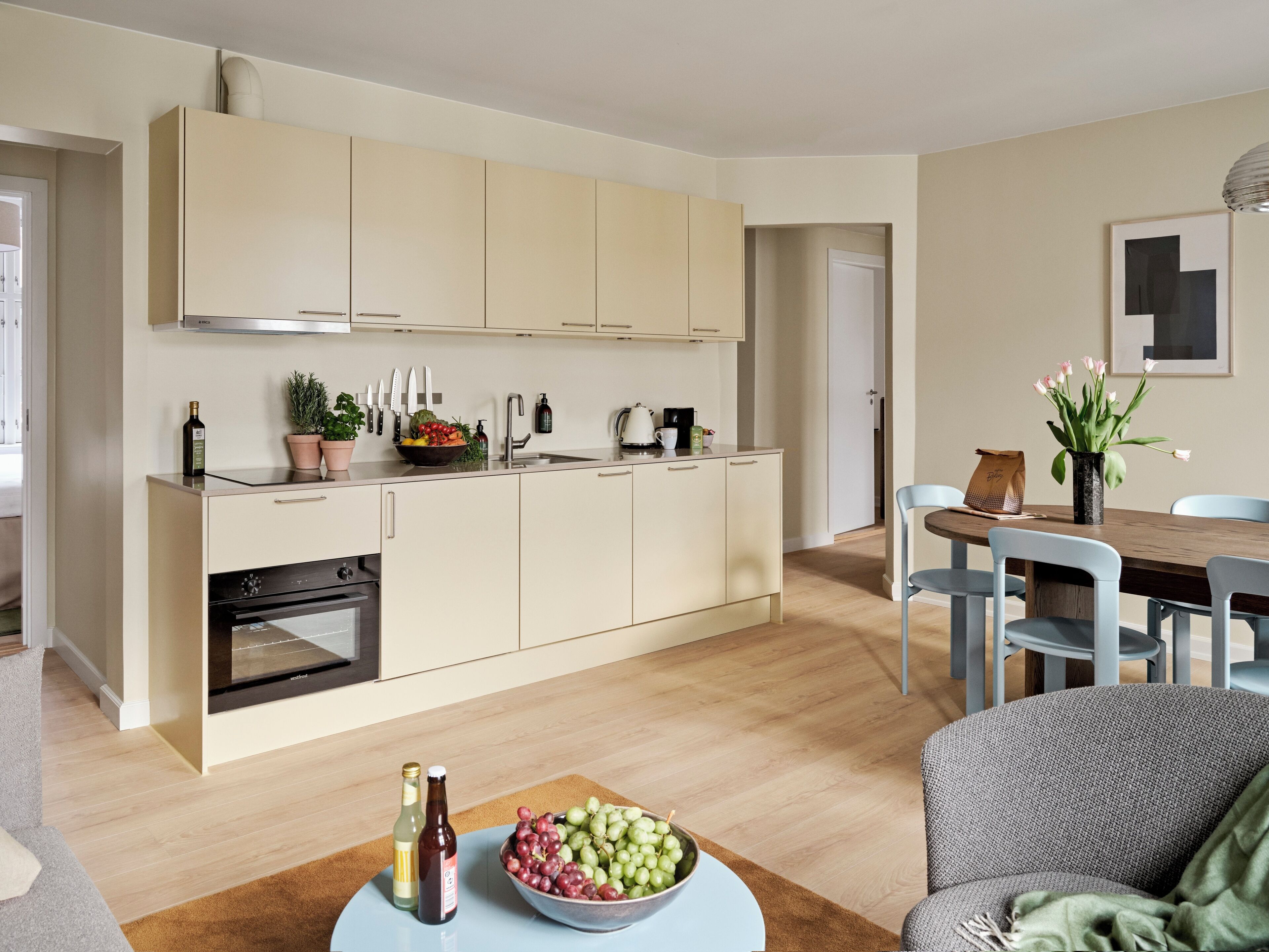 Eine moderne Küche mit einer zentralen Kochinsel, einem Essbereich mit Holztisch und einer Sitzgruppe.