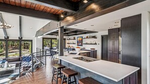 Una cocina moderna con una isla grande, armarios oscuros y vistas al exterior.