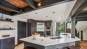 Una cocina moderna con una isla grande, muebles oscuros y vistas al exterior.