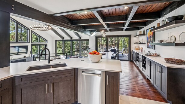 Una cocina moderna con armarios oscuros, una isla grande y vista a un patio exterior.
