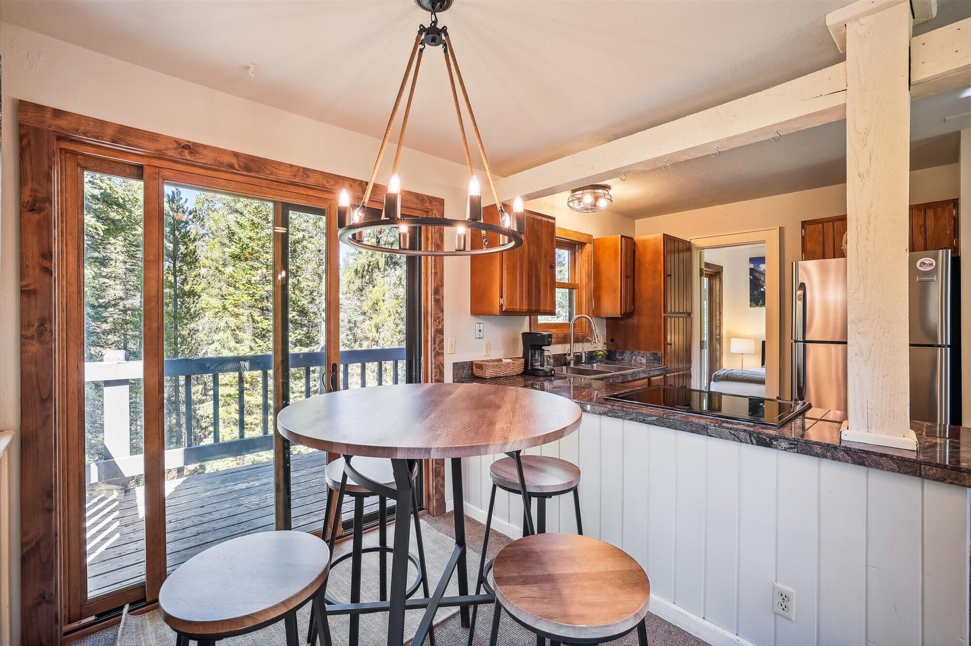 Une cuisine avec une table ronde et des tabourets, des meubles en bois et un réfrigérateur en acier inoxydable.
