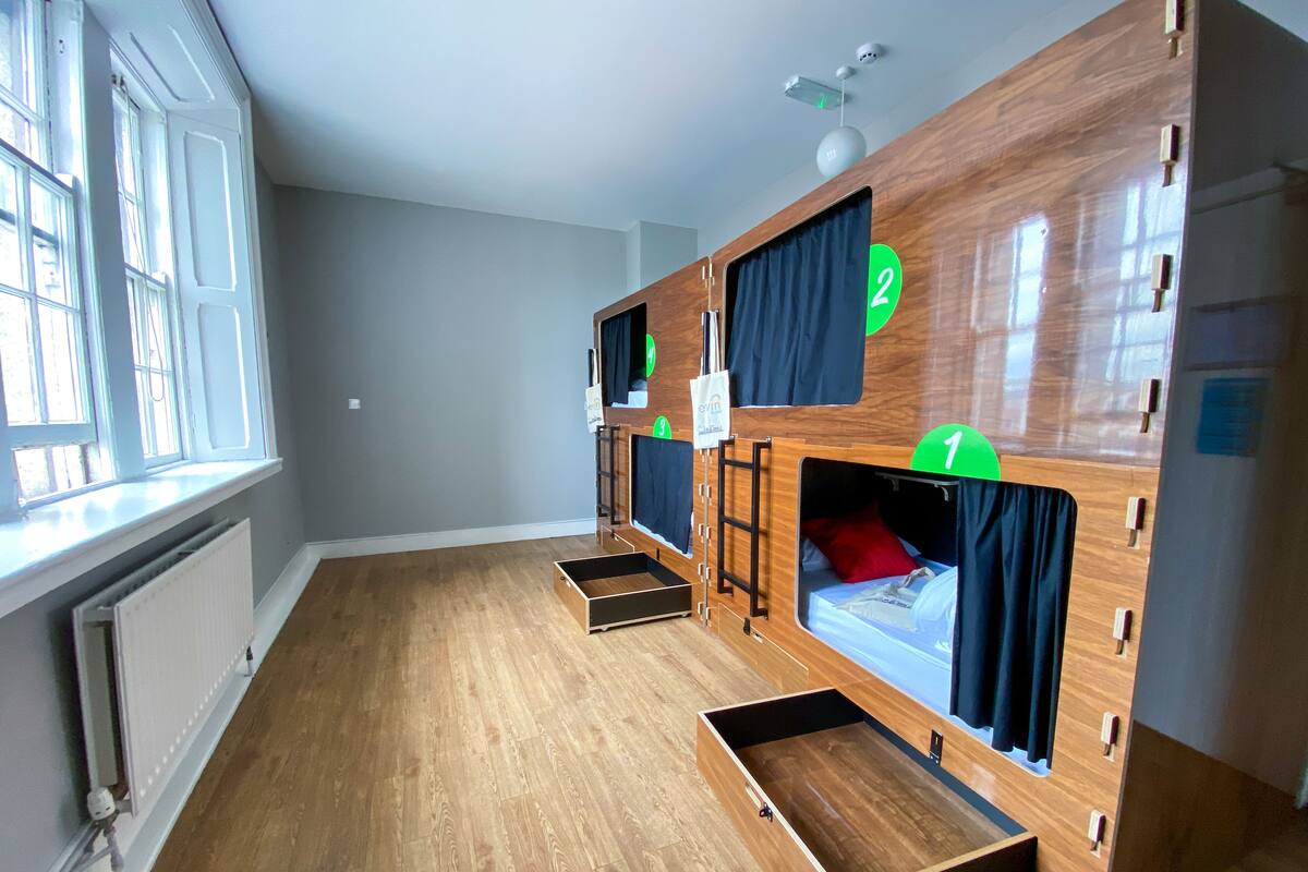 Une chambre avec des lits superposés, une fenêtre et un radiateur.