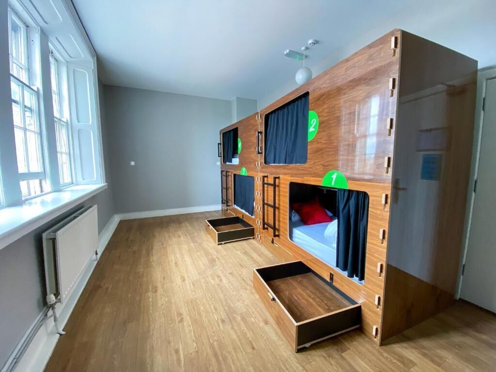 A room with a bunk bed, a window, and a radiator.