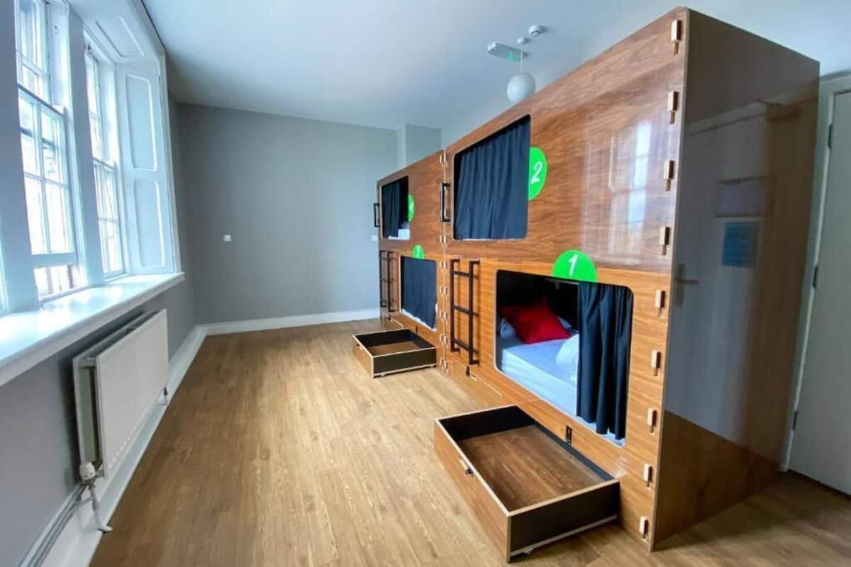 Une chambre avec un lit superposé, une fenêtre et un radiateur.