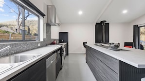 Una cocina moderna con una isla grande, electrodomésticos de acero inoxidable y vistas al exterior.