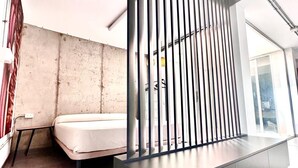A modern room with a metal partition, a bed, and a bench.