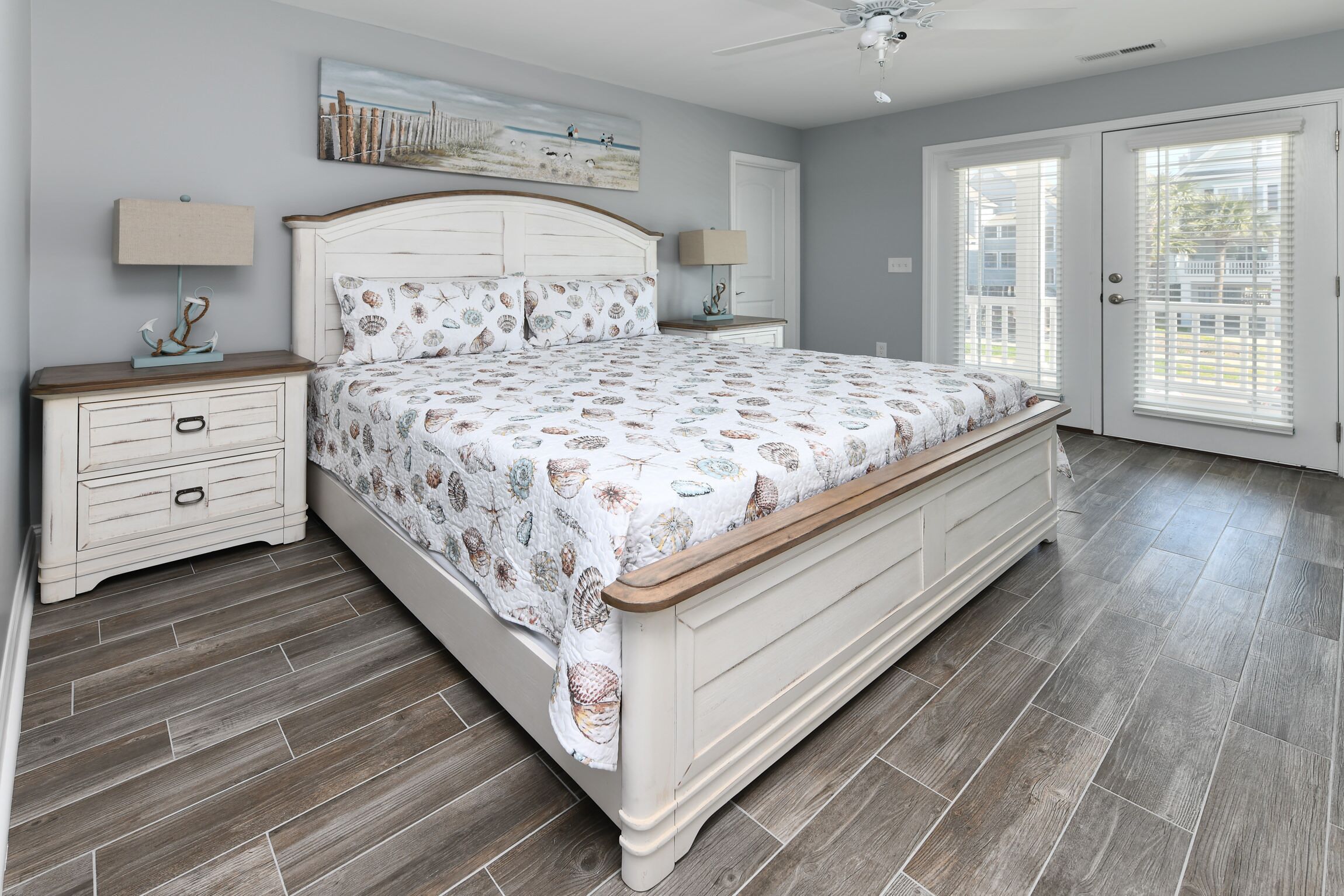 A bedroom with a bed, nightstands, a ceiling fan, and a large window.