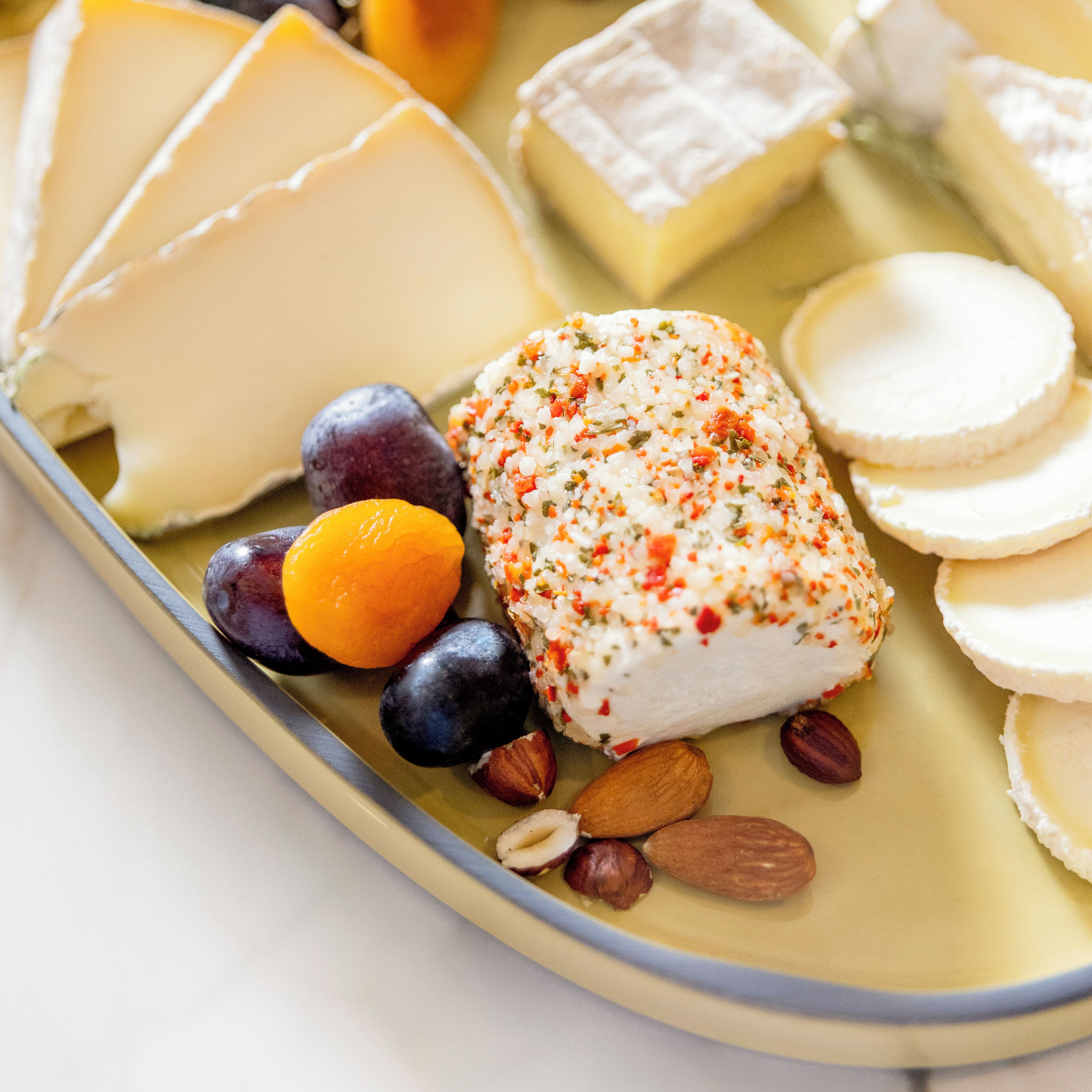 A variety of cheeses and fruits on a plate.