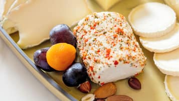 A variety of cheeses and fruits on a plate.