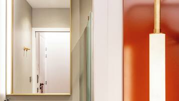 A bathroom with a large mirror, a sink, and a shower area.