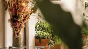 A room with a wooden cabinet, a white table, and potted plants. - Hôtel Pilgrim (Paris)