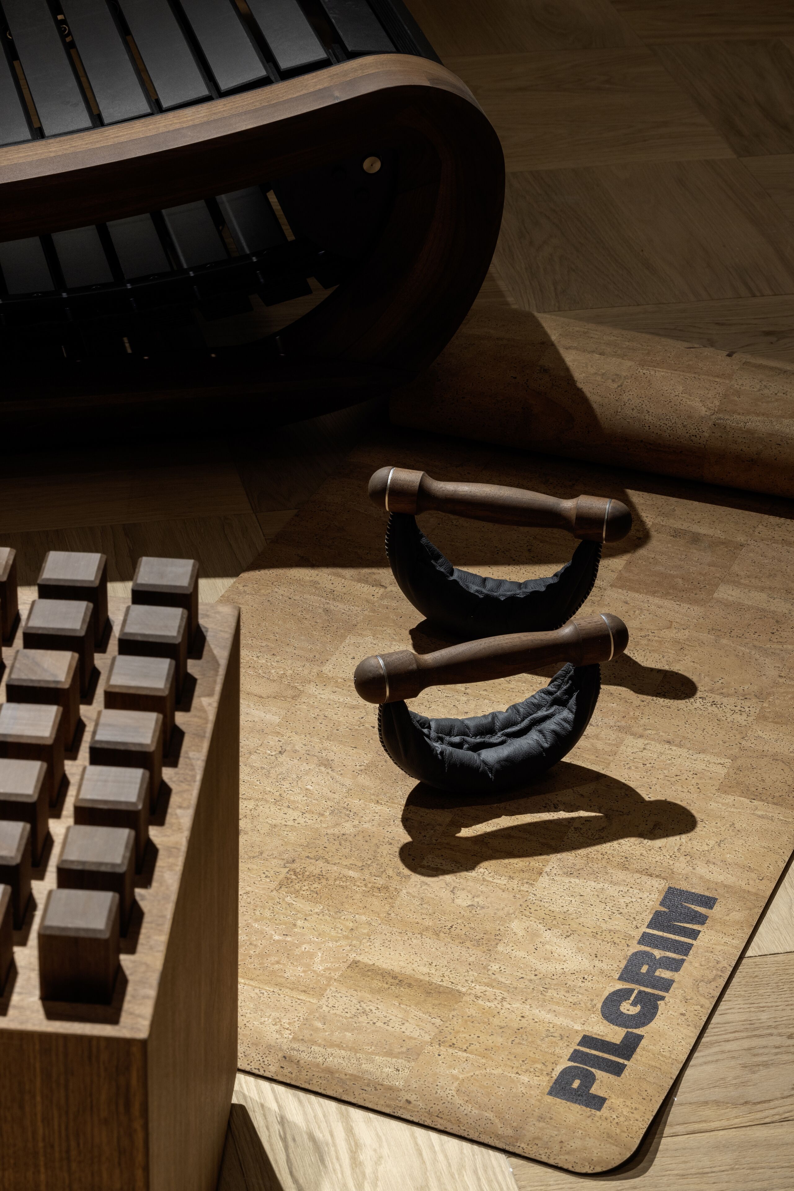 Un bureau en bois avec un clavier, une paire d’haltères et un tapis sur lequel est inscrit le mot « PILGRIM ».