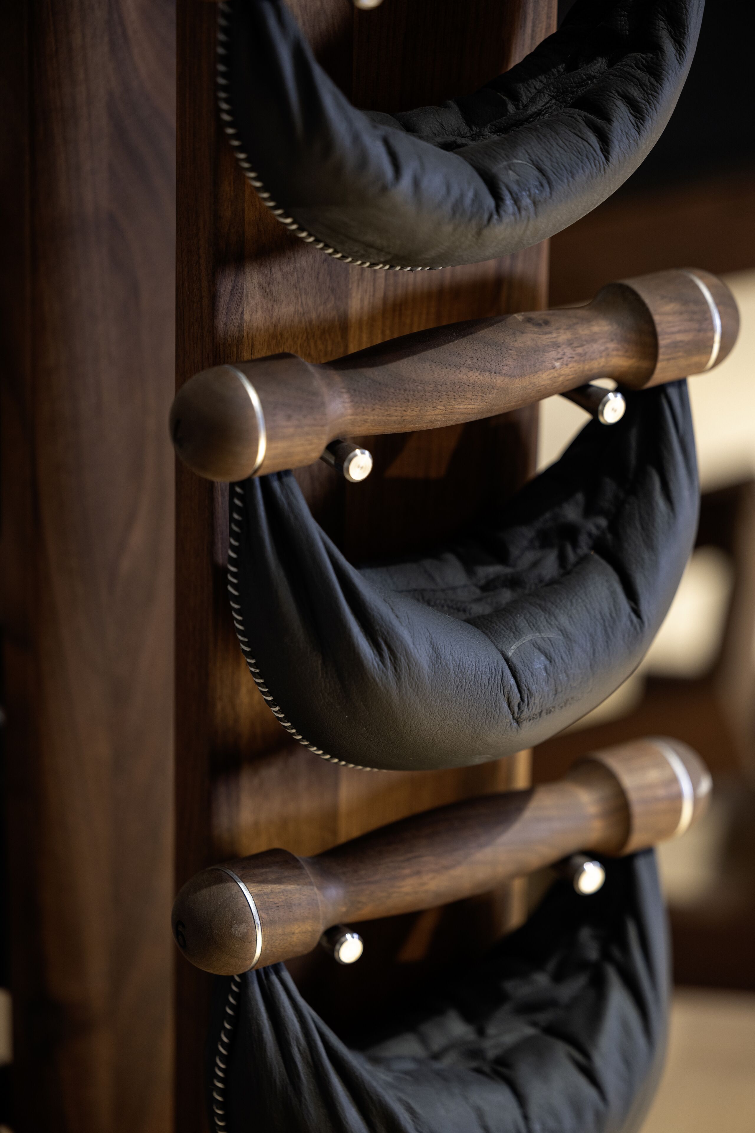 A wooden chair with a black cushion and metal legs.
