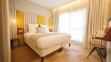 Habitación de hotel con una cama grande, mesitas de noche, una silla y vistas al exterior.