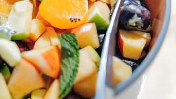 A bowl of fruit salad with various fruits and mint leaves.