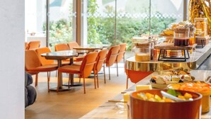 A modern dining area with a buffet setup, including a variety of food items and a decorative floral arrangement. - Hôtel Pilgrim (Paris)