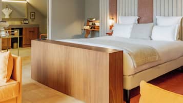 Una habitación de hotel moderna con una cama grande, una mesita de noche de madera, un escritorio pequeño y una silla.