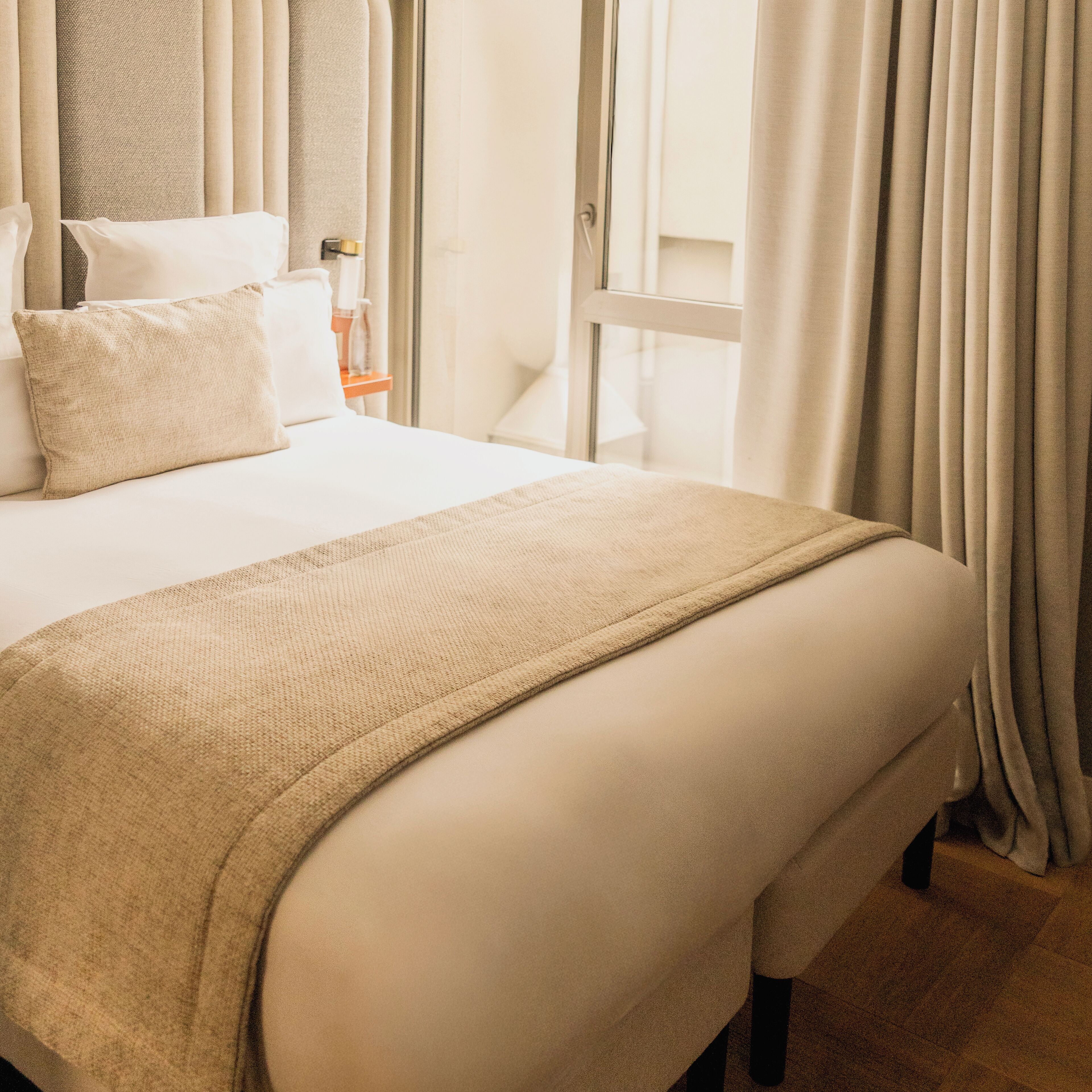 Een hotelkamer met een groot bed, een nachtkastje, een raam met gordijnen en uitzicht op het exterieur.