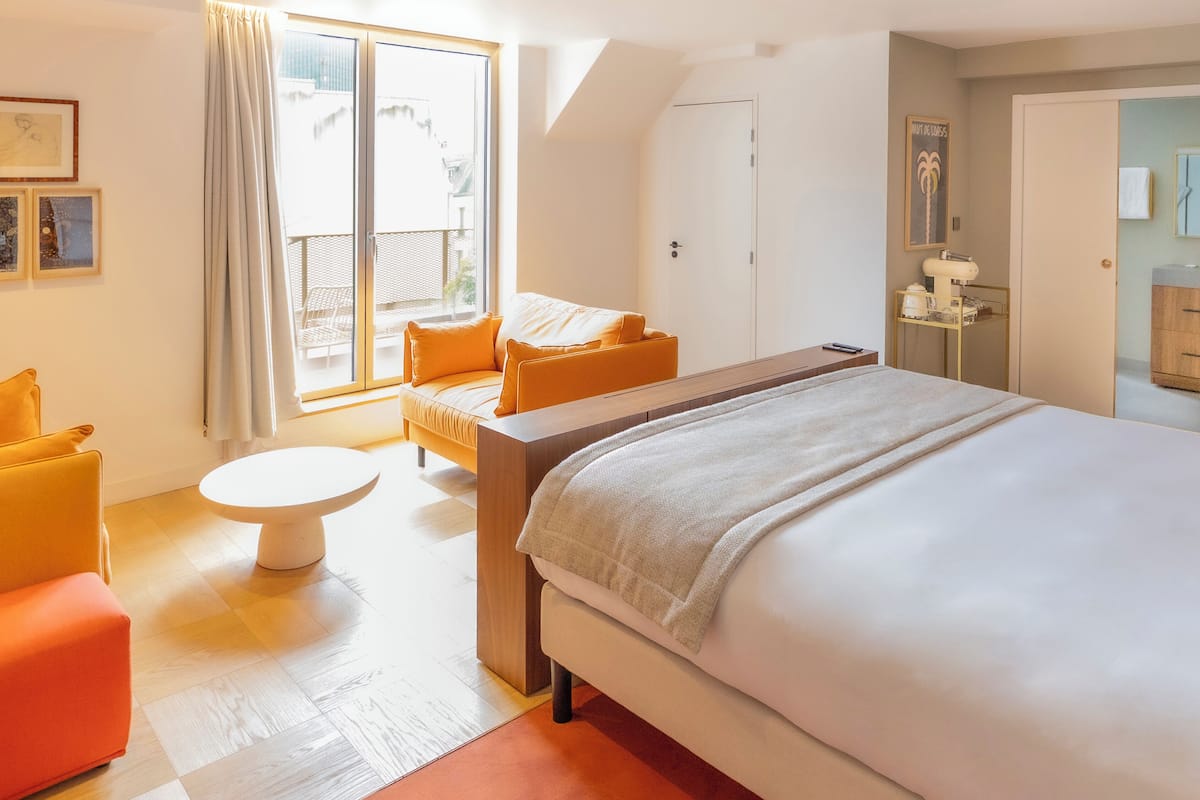 Une chambre d’hôtel avec un grand lit, une petite table, un canapé et un balcon avec vue.