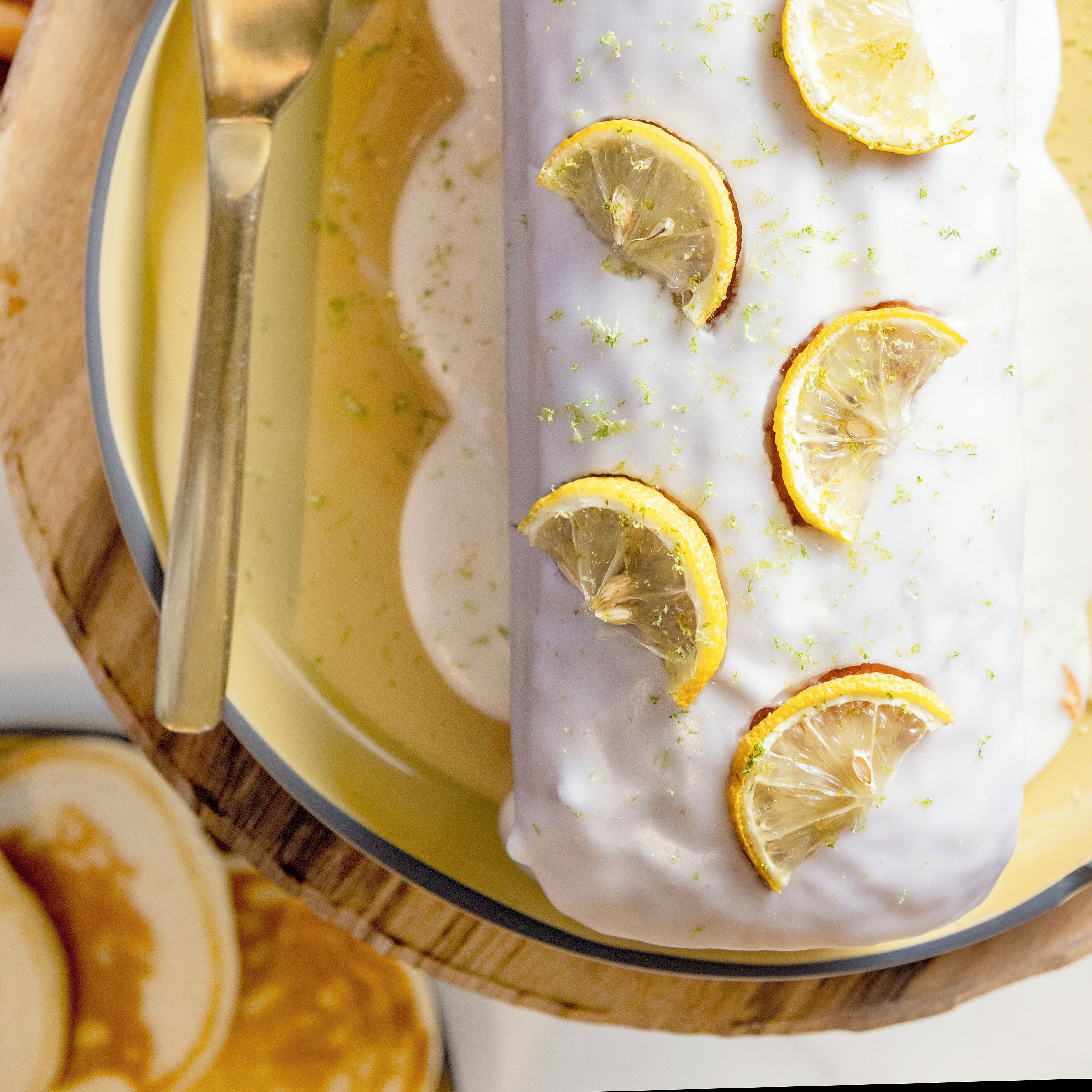 Un dessert garni de tranches de citron, servi dans une assiette avec une cuillère.