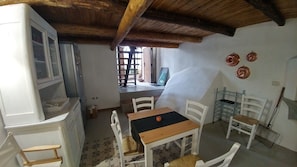 A room with a wooden ceiling, a table with chairs, a window, and a door.