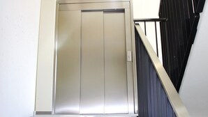 A modern elevator with a metallic finish, located in a building with a white wall and a black railing. - Superb Loft In The Center Of Lausanne (Lausanne)