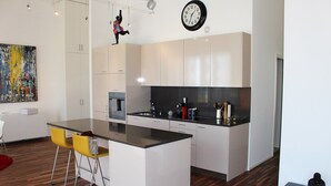 A modern kitchen with white cabinets, a black countertop, and a central island with yellow chairs. - Superb Loft In The Center Of Lausanne (Lausanne)